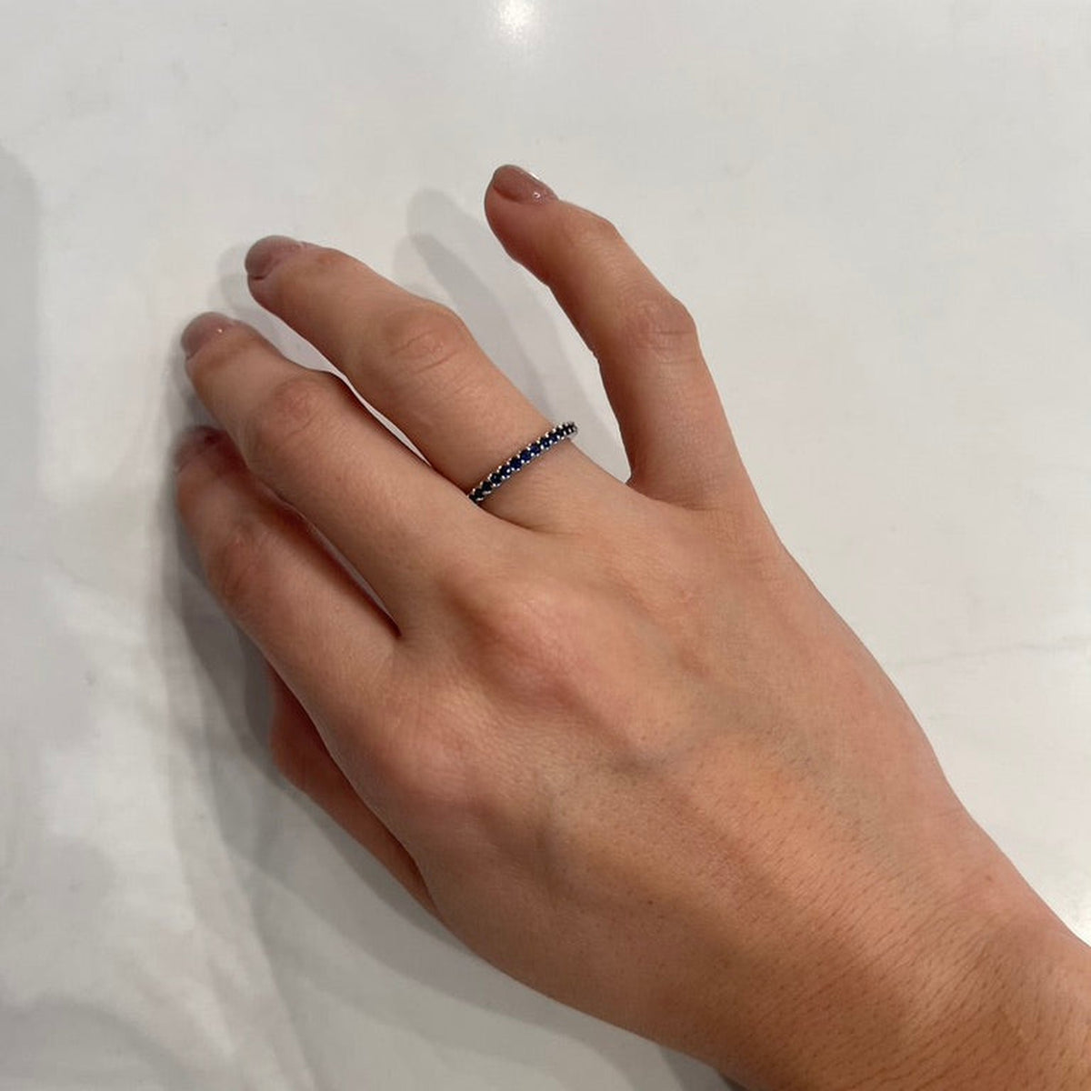 AD121BS Blue Sapphire Shared Prong Eternity Band worn on hand