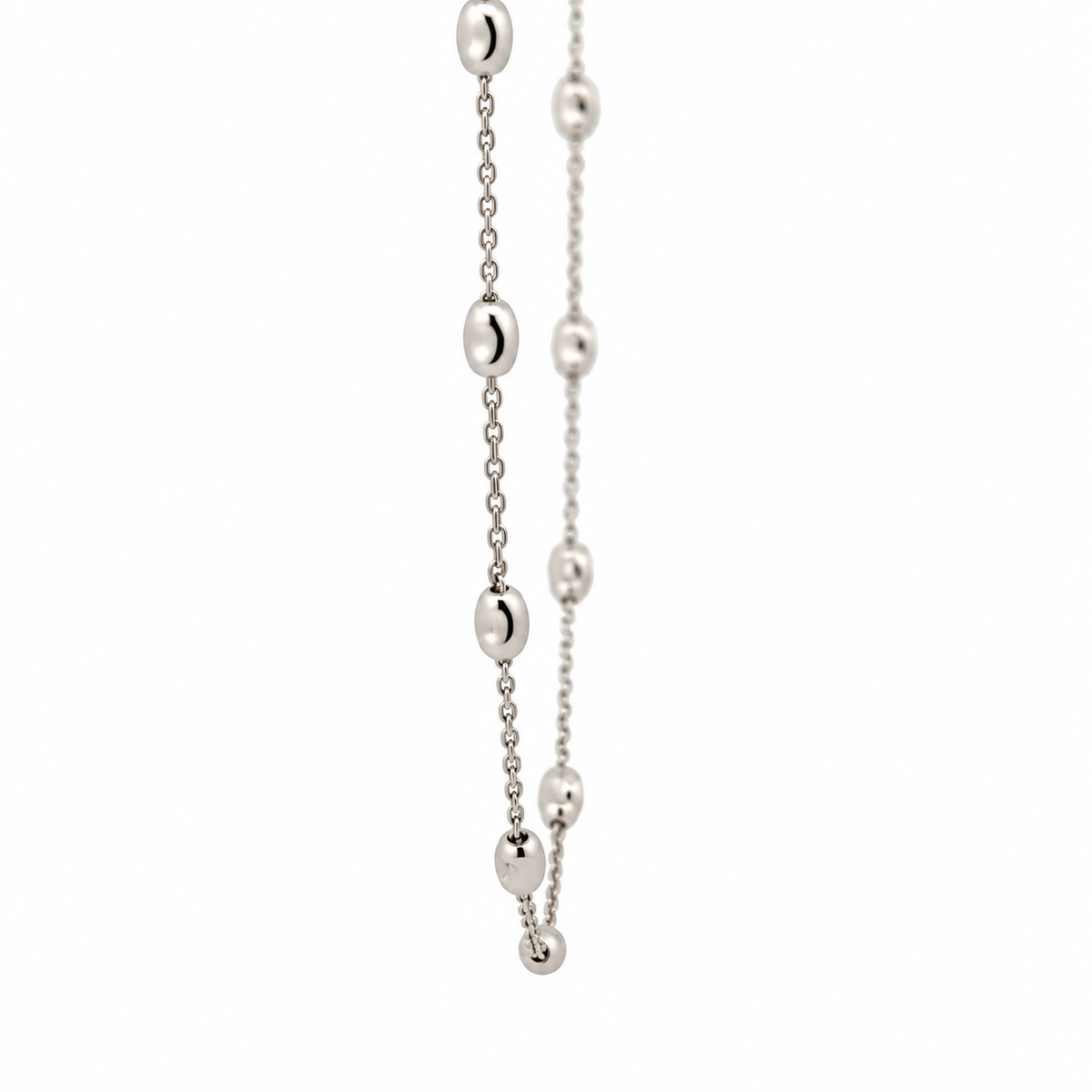 Close-up of polished oval gold beads spaced along a fine 14KT white gold necklace chain.